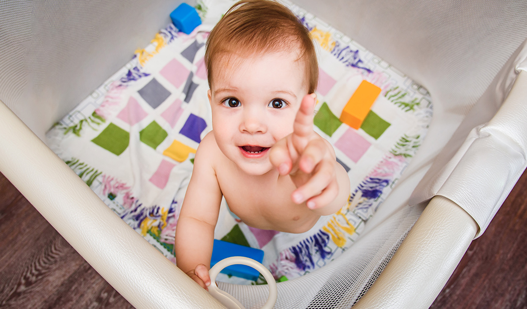 little boy playing in playpen