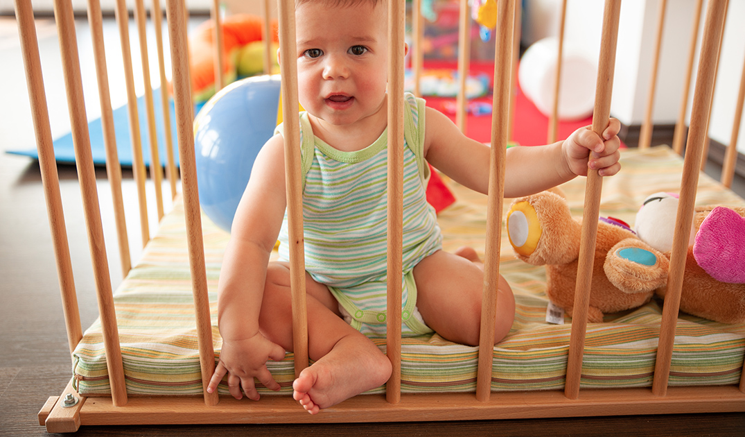 baby in wooden playpen