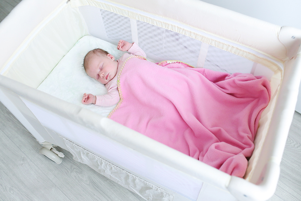 Baby girl sleeping in portable crib
